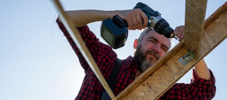 Handwerker bohrt Holzbrett mit Elektrowerkzeug 