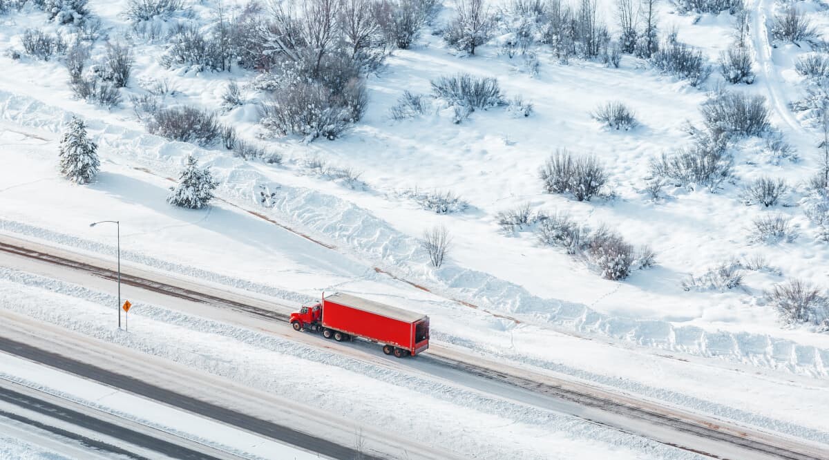 roter LKW fährt durch eine Schneelandschaft